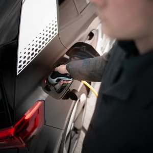 Person verbindet sein Elektroauto mit einer Ladesäule